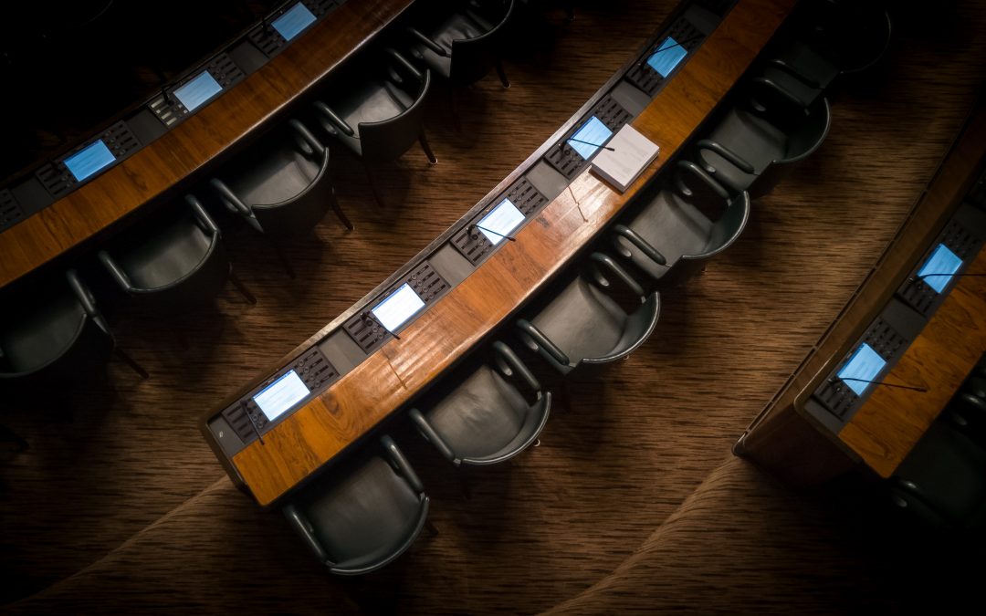 A dark courthouse with long tables and rows of chairs
